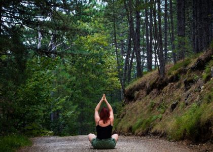 Woman practicing yoga in a tranquil forest setting, symbolizing peace and nature.