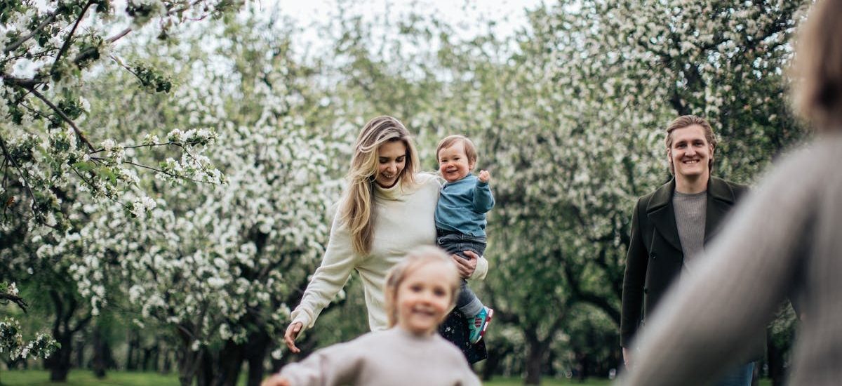 A joyful family enjoys a playful day outdoors amidst blossoming trees in spring.