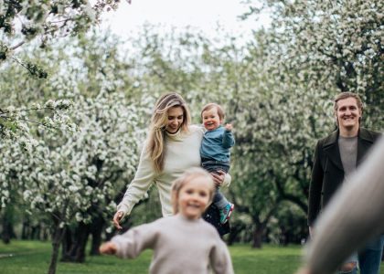 A joyful family enjoys a playful day outdoors amidst blossoming trees in spring.