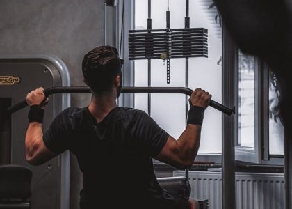 Back view of a man exercising with lat pulldown machine in the gym.